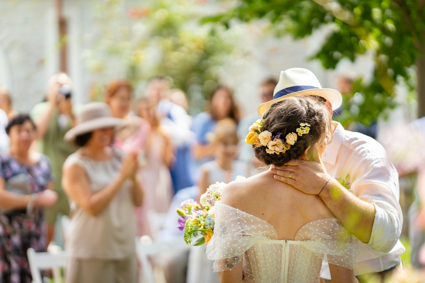 Bride and groom embracing during an outdoor wedding ceremony.