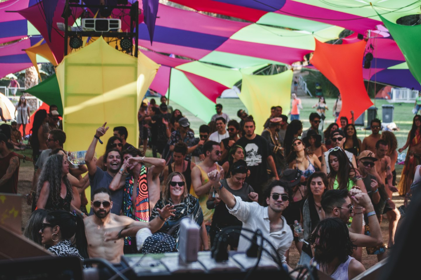 People dance and celebrate under a colorful fabric canopy.
